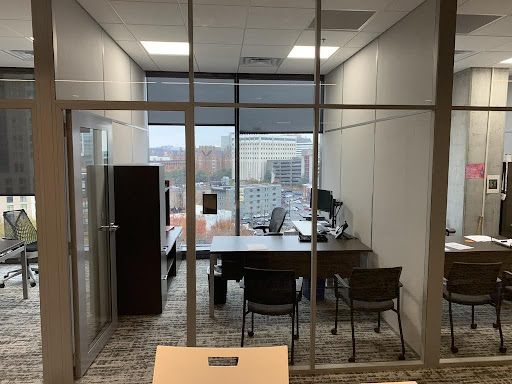 View of an office with a desk, cabinet, and a few chairs, with a view outside of Fort Wayne